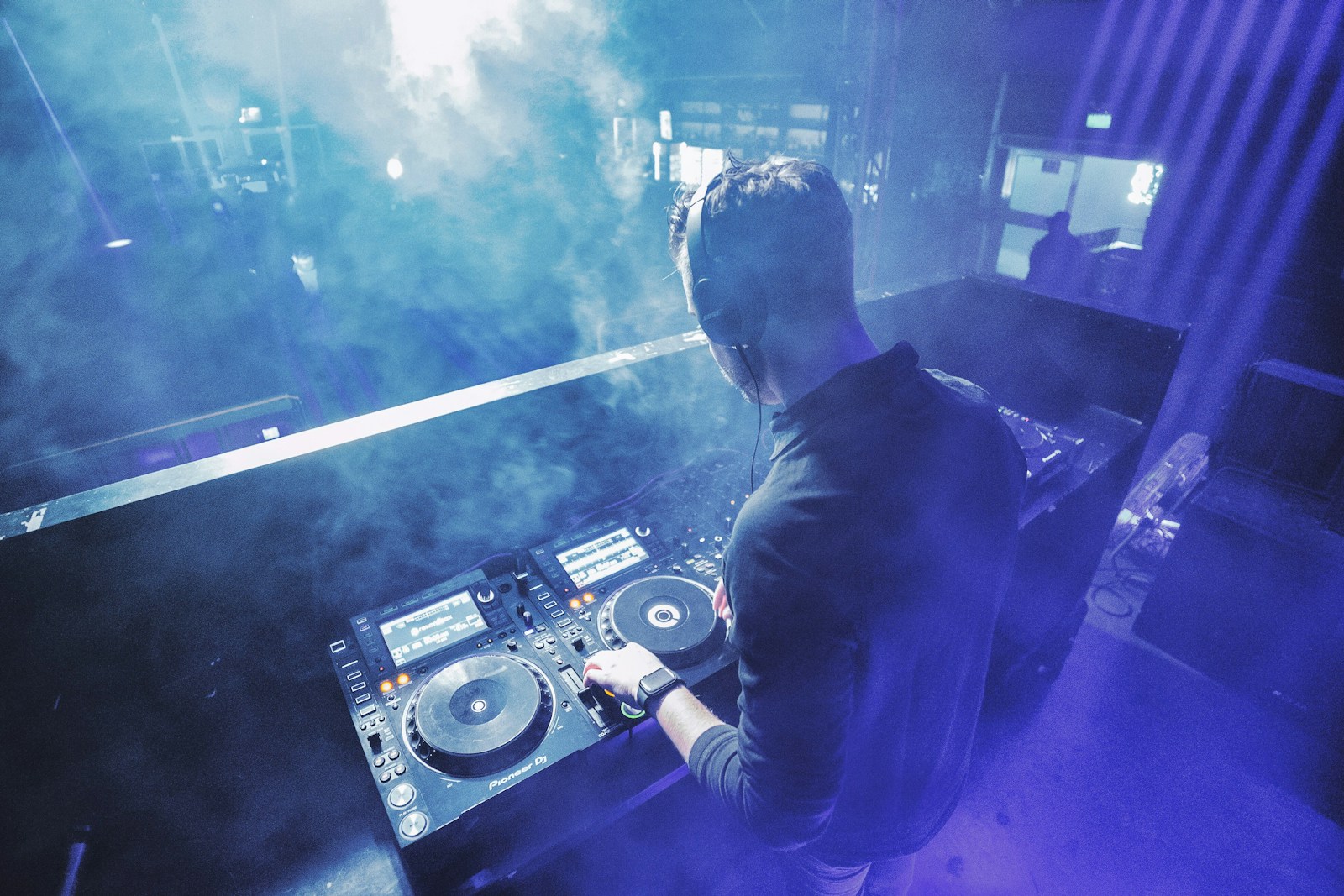 DJ em apresentação, operando uma mesa de som em um palco iluminado